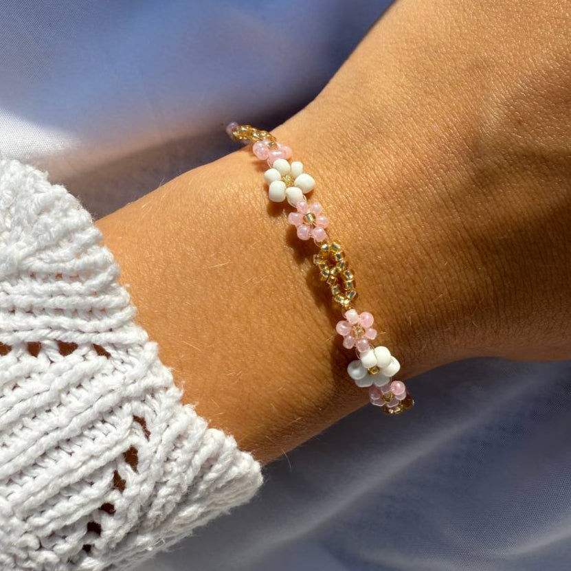 Perlenarmband mit weißen und rosanen Blumen und goldener Verzierung