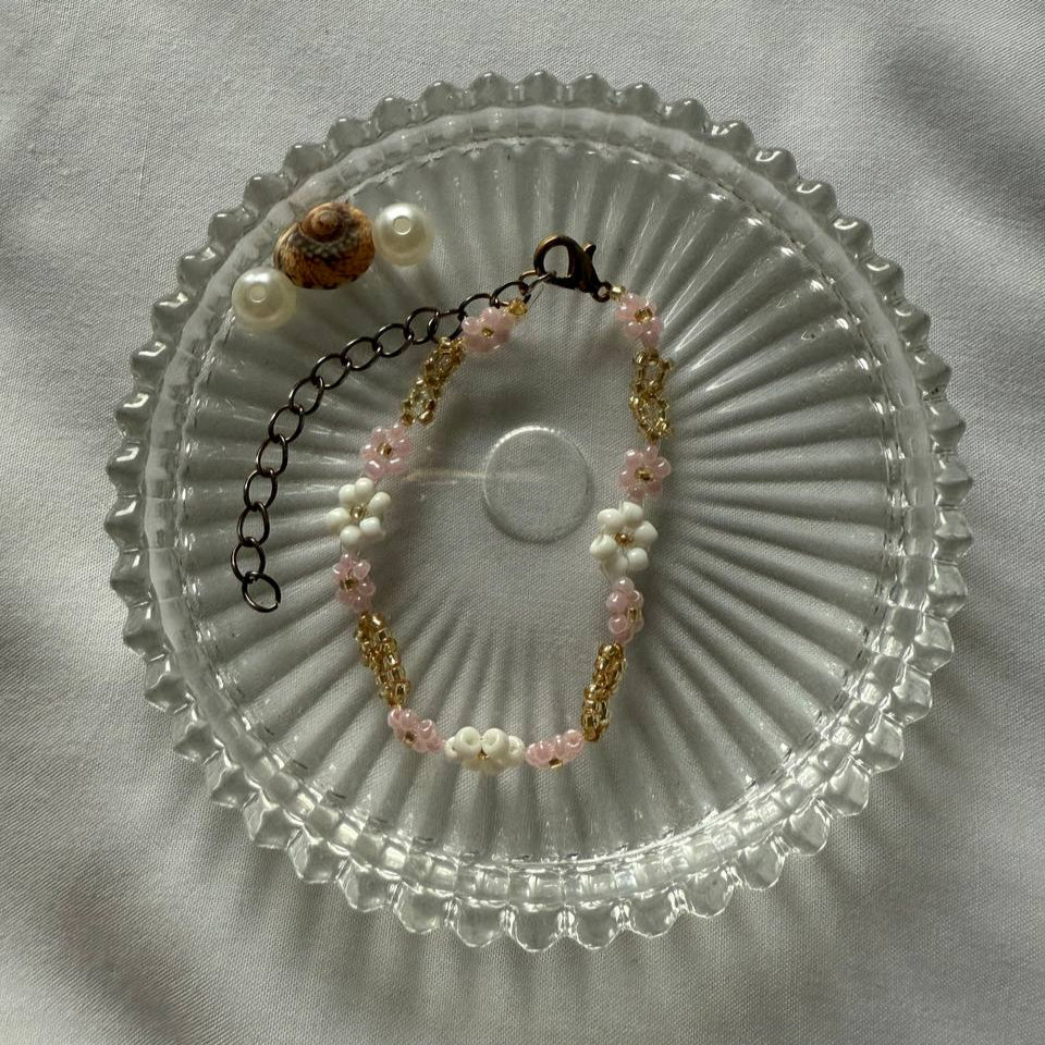 Perlenarmband mit weißen und rosanen Blumen und goldener Verzierung