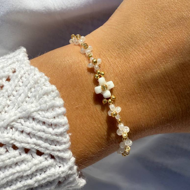 Perlenarmband mit weißen Blumen und goldenen Akzenten