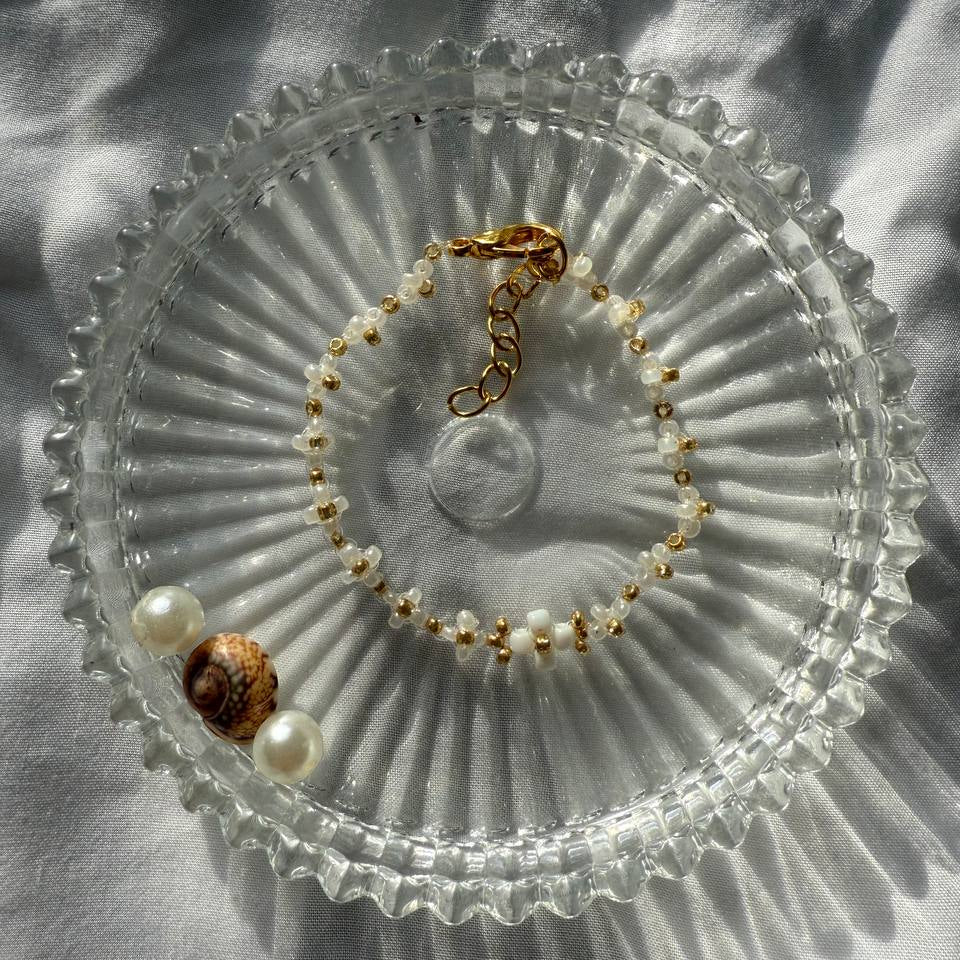 Perlenarmband mit weißen Blumen und goldenen Akzenten