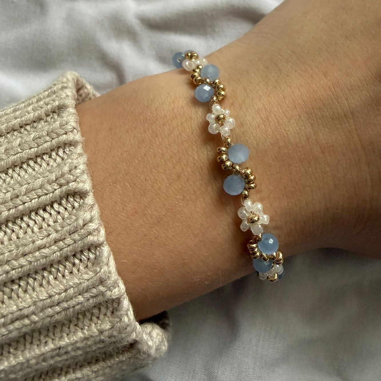 Perlenarmband mit weißen Blumen und blauem Wellenmuster