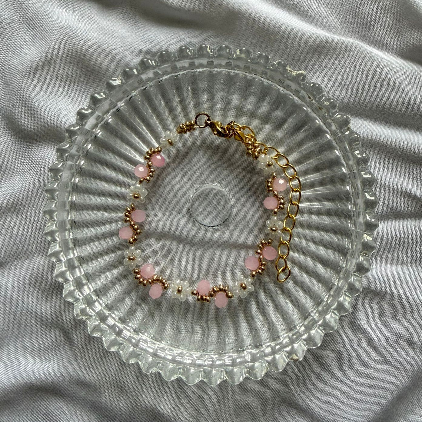 Perlenarmband mit weißen Blumen und rosanem Wellenmuster