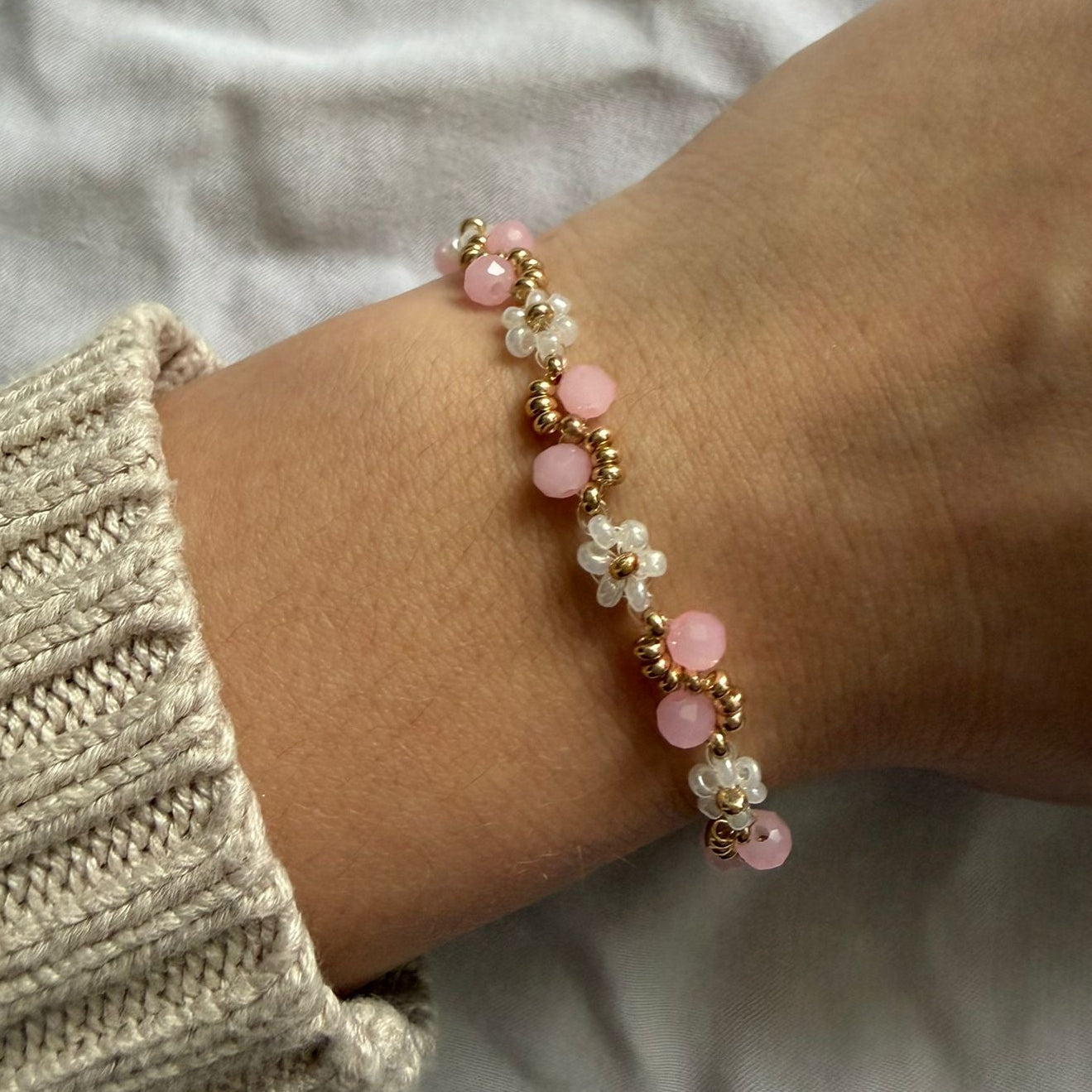 Perlenarmband mit weißen Blumen und rosanem Wellenmuster