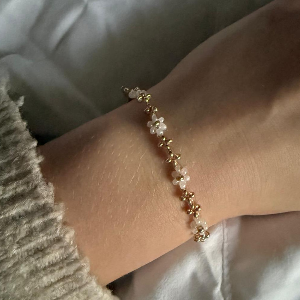 Perlenarmband mit weißen Blumen und goldene Details