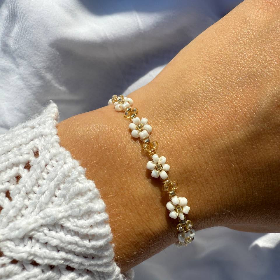 Perlenarmband mit weißen Blumen und goldenen Akzenten