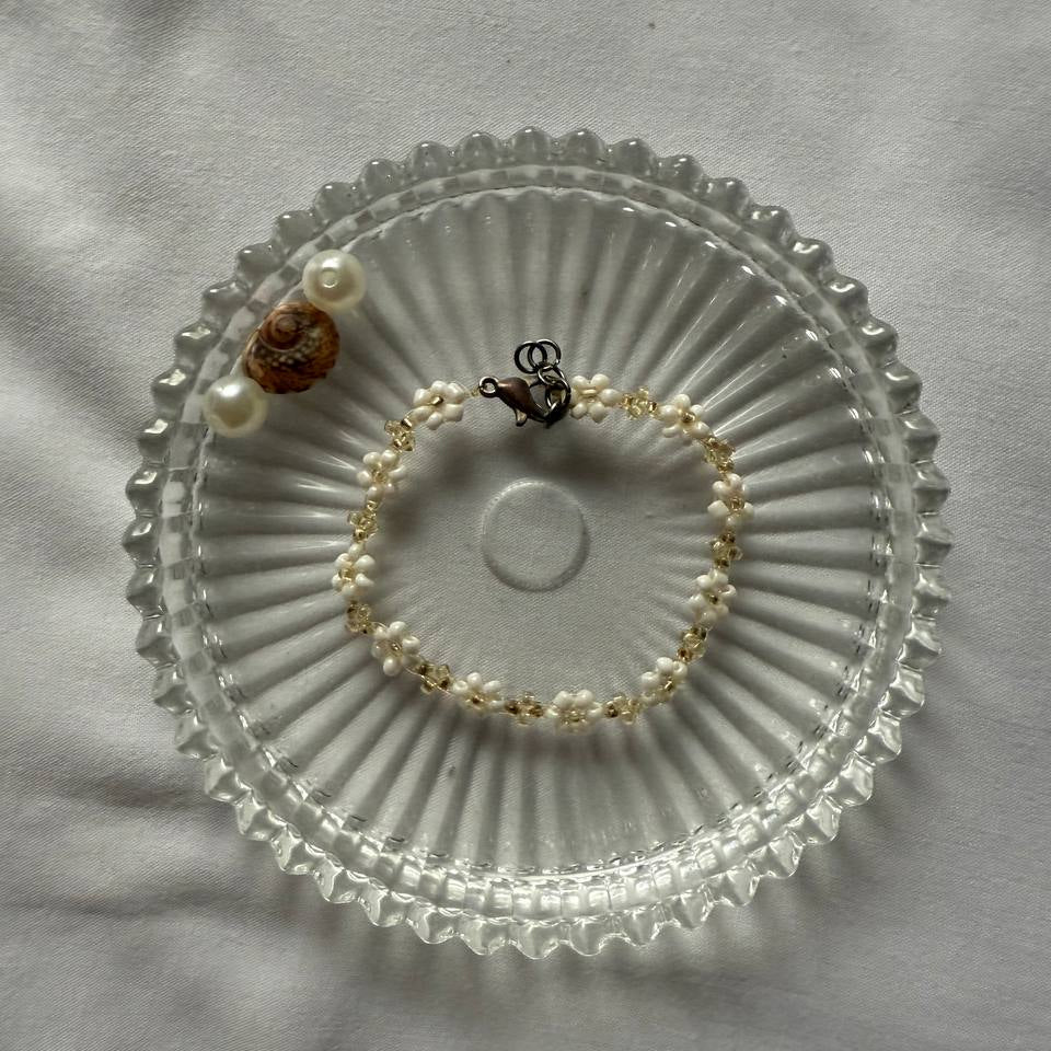 Perlenarmband mit weißen Blumen und goldenen Akzenten